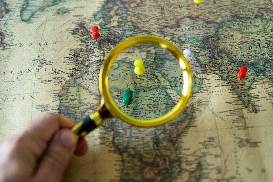 Paper map with magnifying glass and route pins